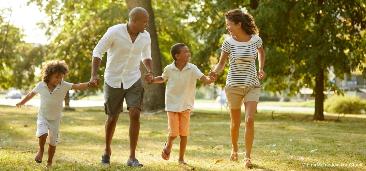 Familie läuft im Sommer durch einen Park