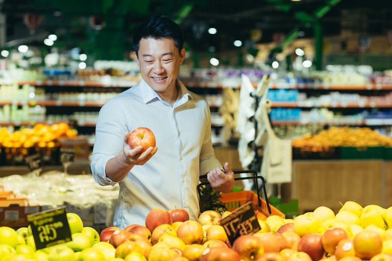 Mann am Marktstand hält Apfel in der Hand