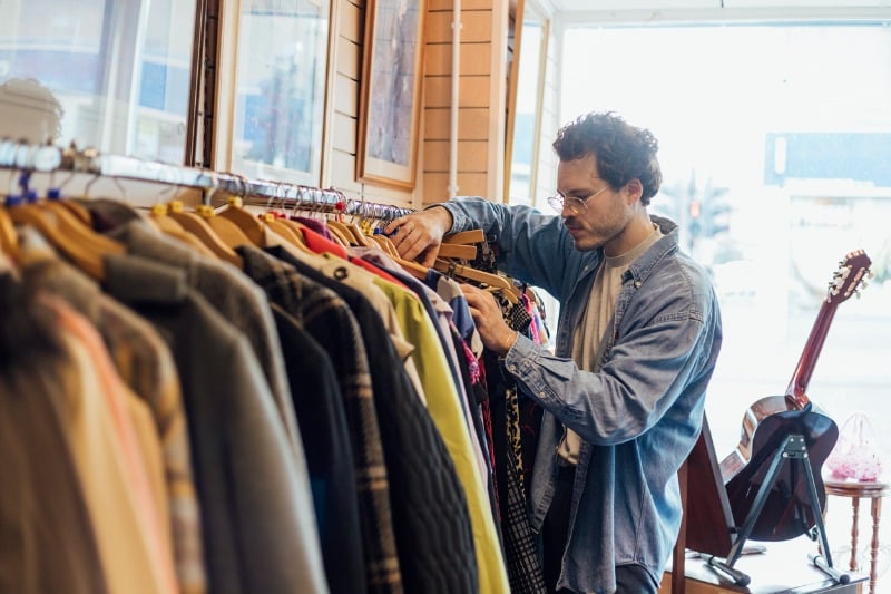 Junger Mann schaut sich Kleidung in einem Geschäft an