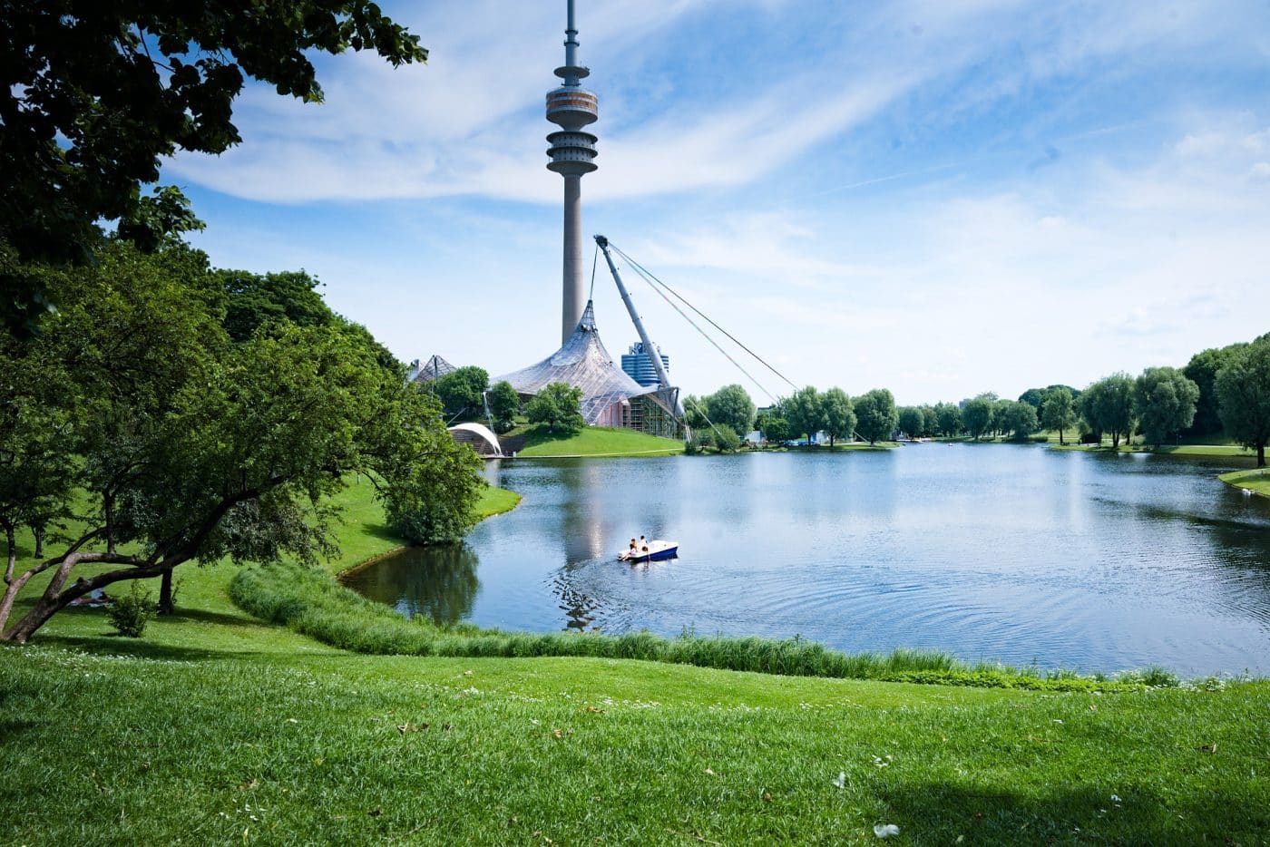 Olympiapark mit Turm und See im Sommer.