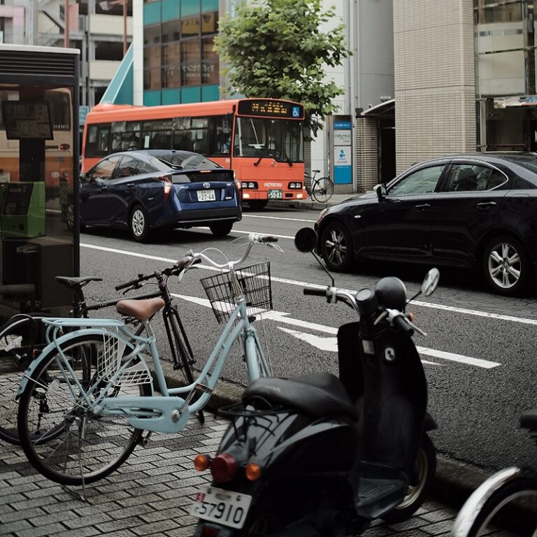 Aufnahmen einer Straße mit Autos, Fahrrädern, einem Roller und einem Bus