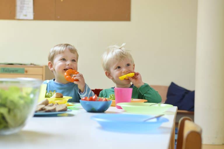 Zwei Kinder essen frische Paprika.