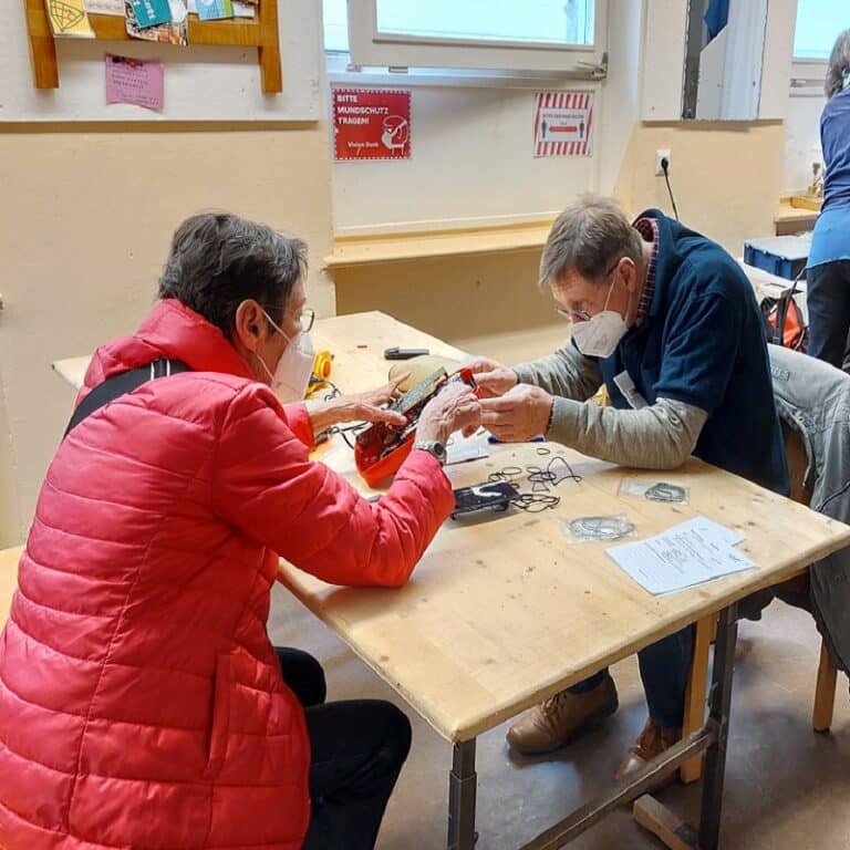 Zwei Menschen reparieren ein Elektrogerät im Repair Café