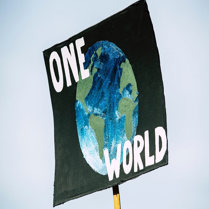 Plakatschild "One World" mit Weltkugelmotiv.