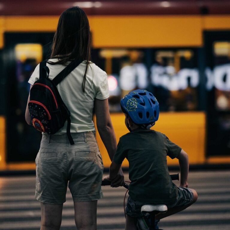 Frau mit Kind auf dem Fahrrad vor einer U-Bahn